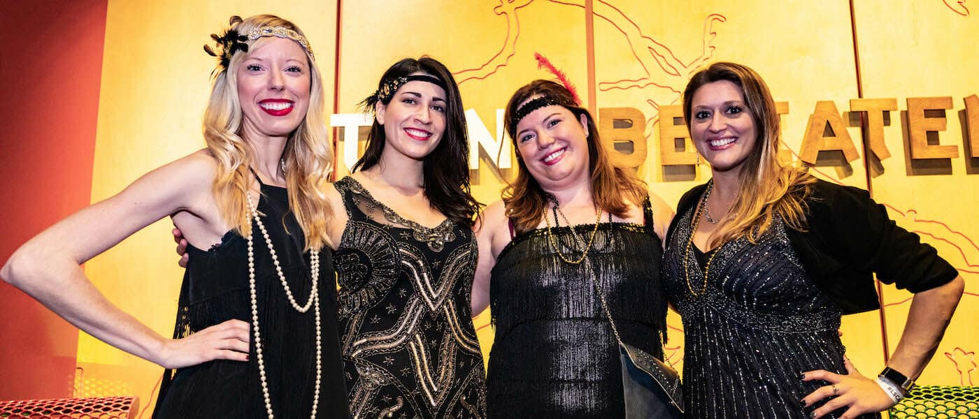 A photo of guests at a similar speakeasy event at the Liberty Science Center. They are wearing 1920s style clothing.