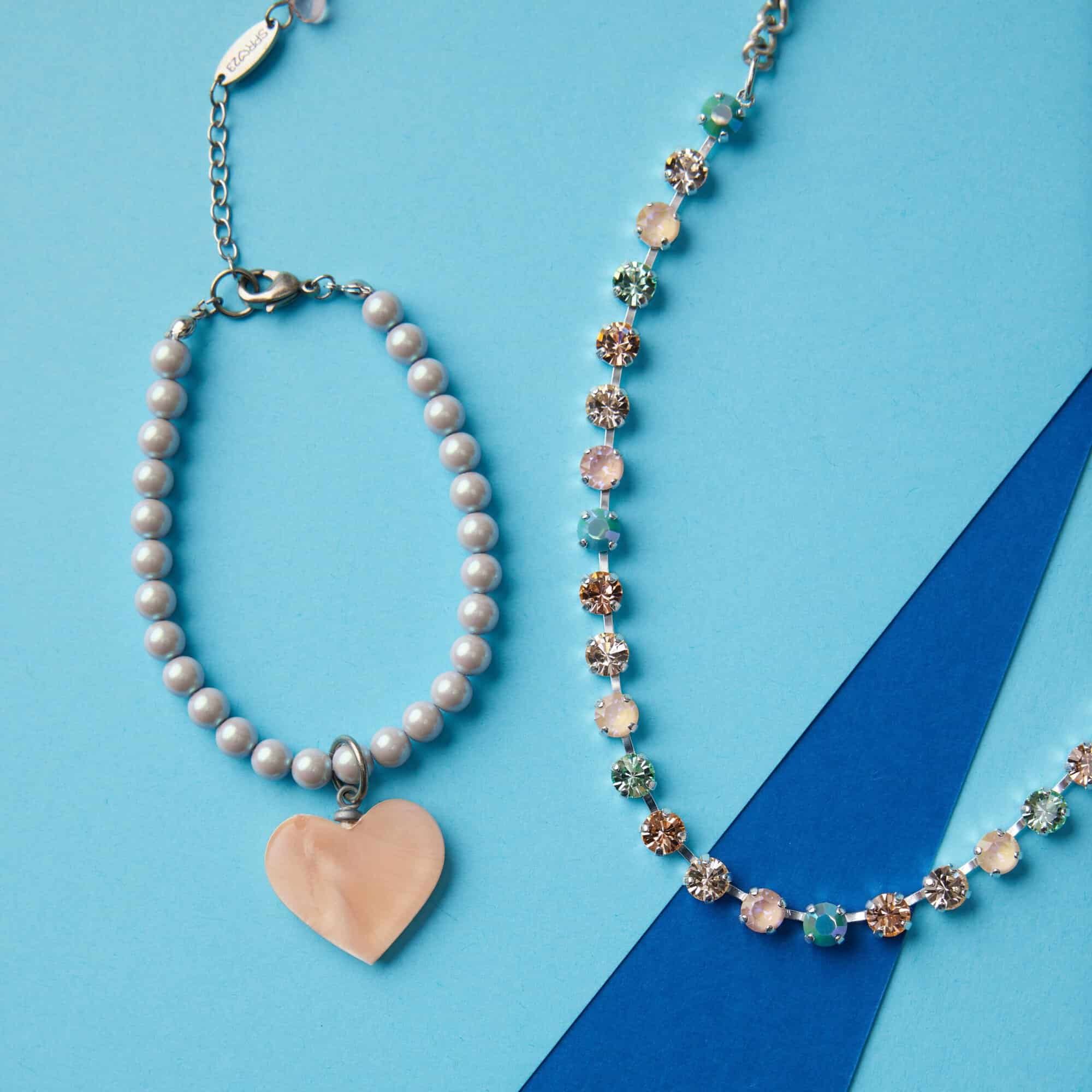 A photo with a blue background featuring the "Enticing" jewelry within the Spring 2023 Collection.