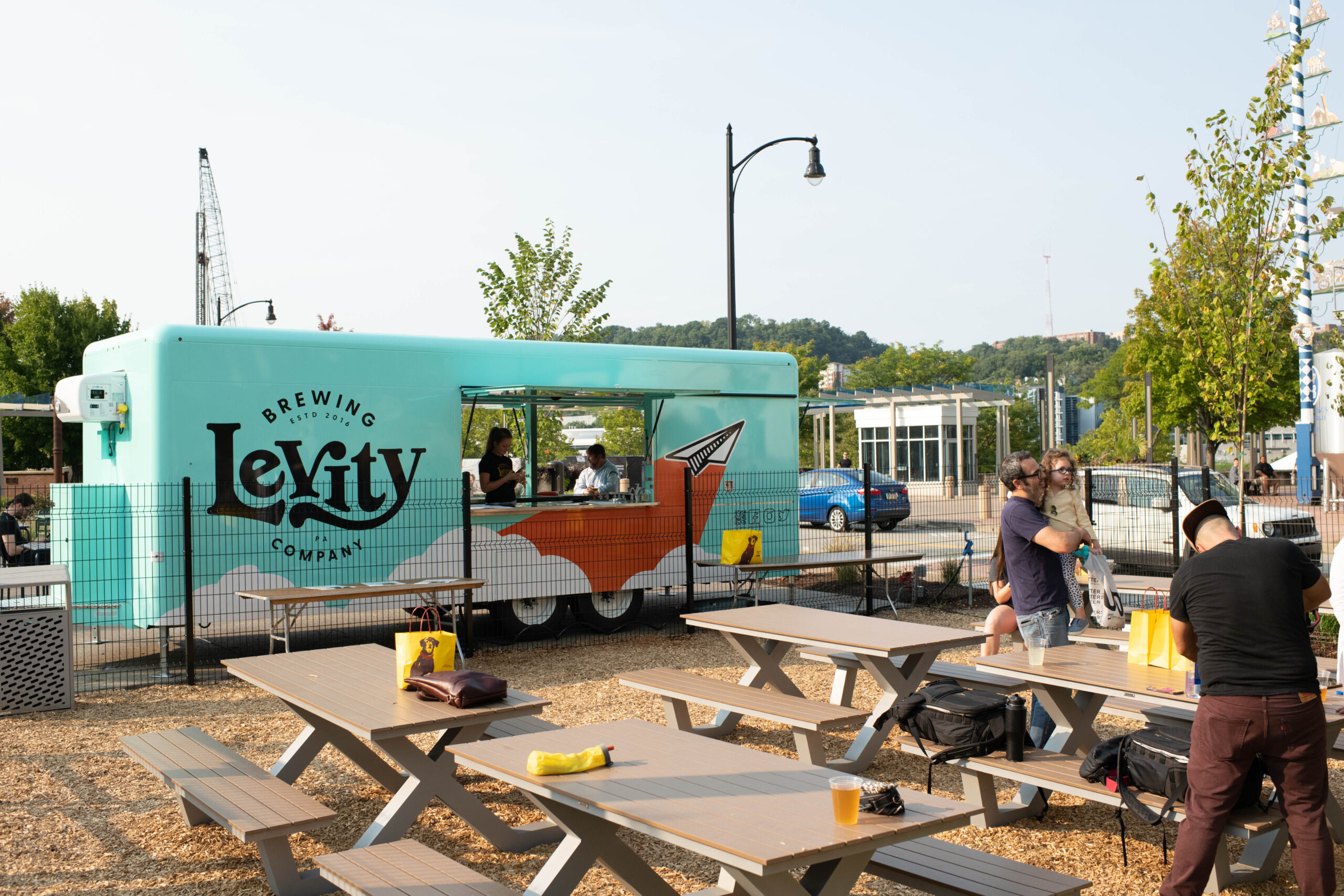 A photo of picnic tables for outdoor dining and a Levity Brewing Company truck outside.