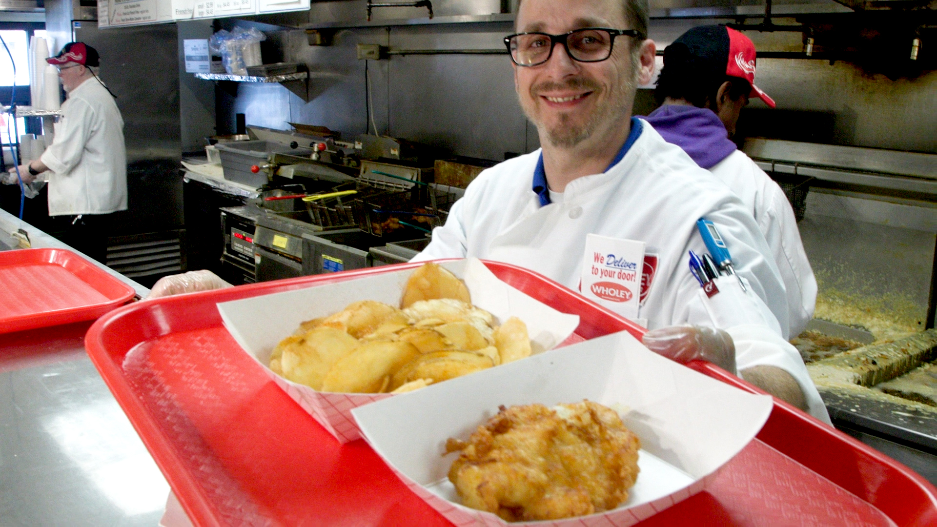 A photo of a worker serving fish and chips at Wholey's.