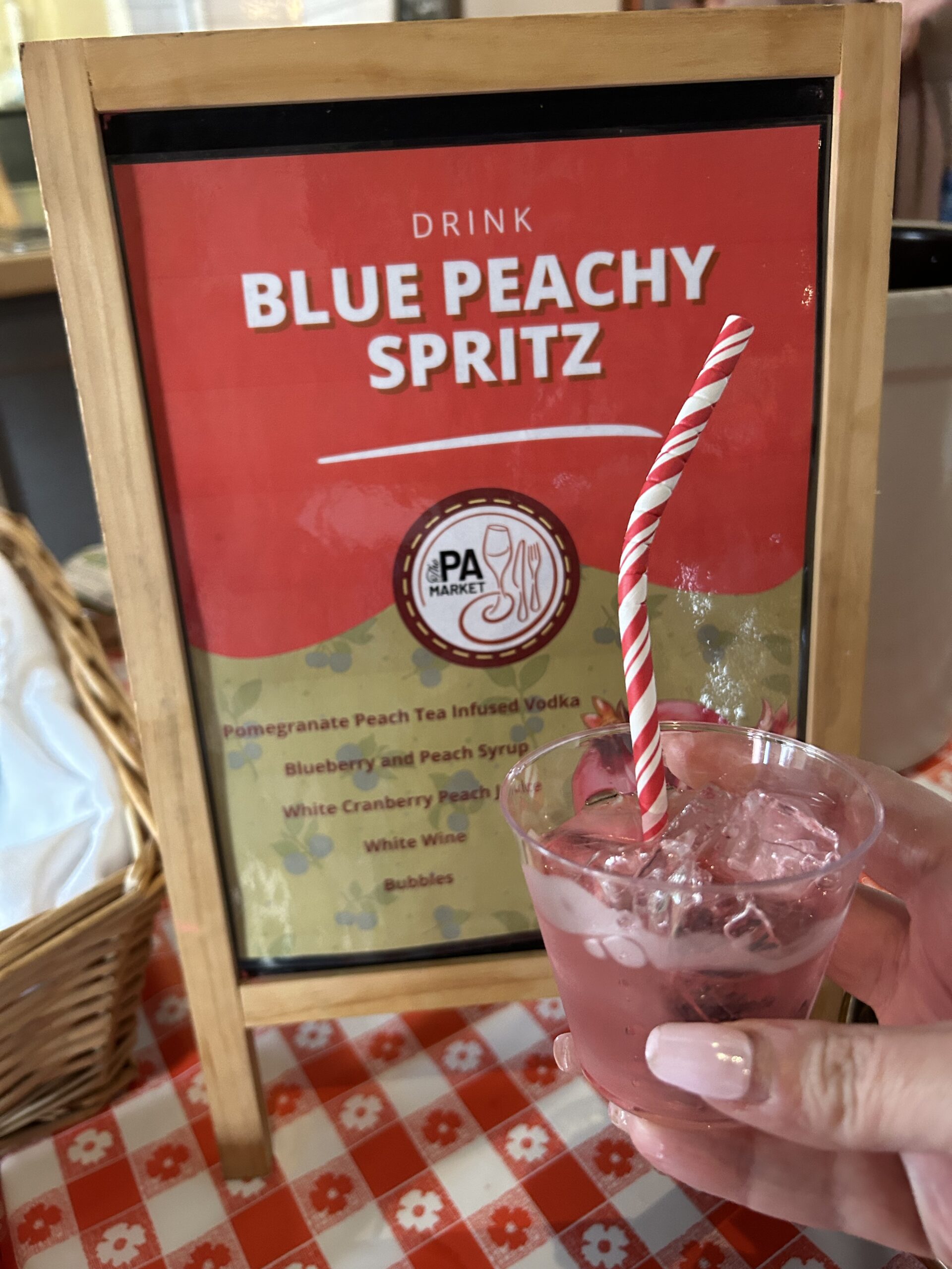 A photo of the Blue Peachy Spritz sample drink and a sign with the ingredients.