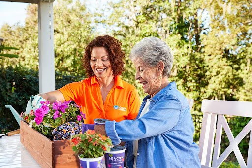 A photo of an older woman and a Comfort Keepers worker gardening together.