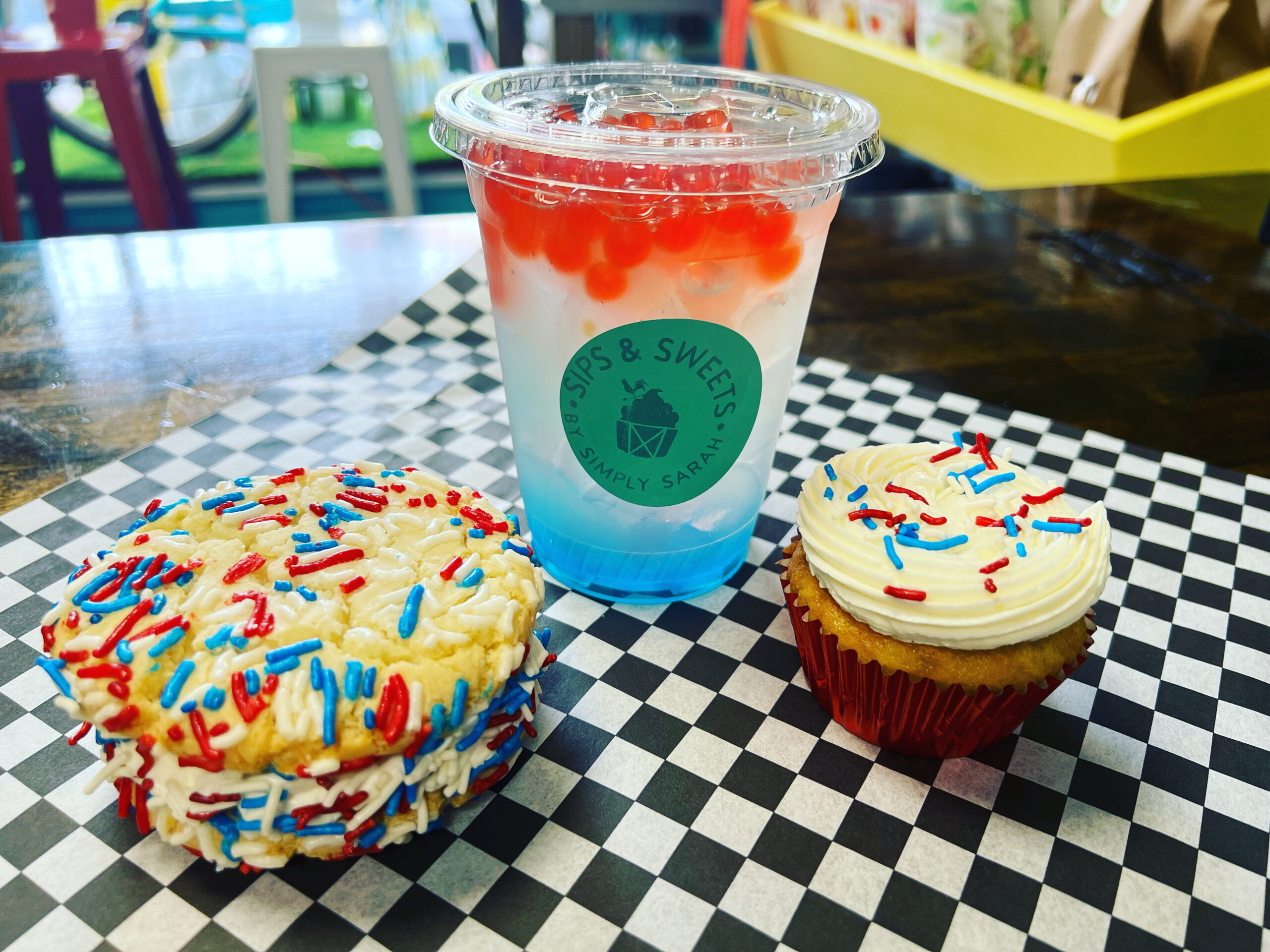 A photo of a 4th of July themed cookiewich, bubble tea, and cupcake at Sips & Sweets.