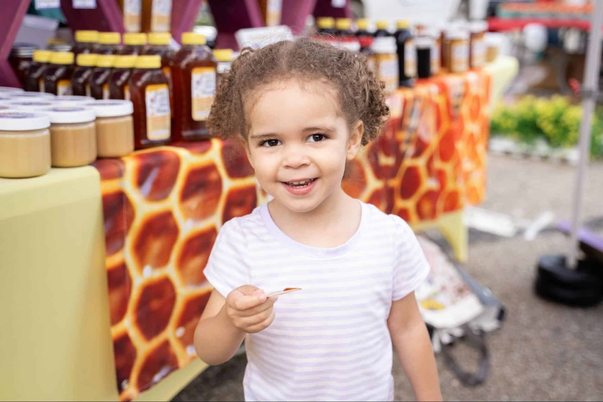 A child holding a honey sample at Moon Market & Music.
