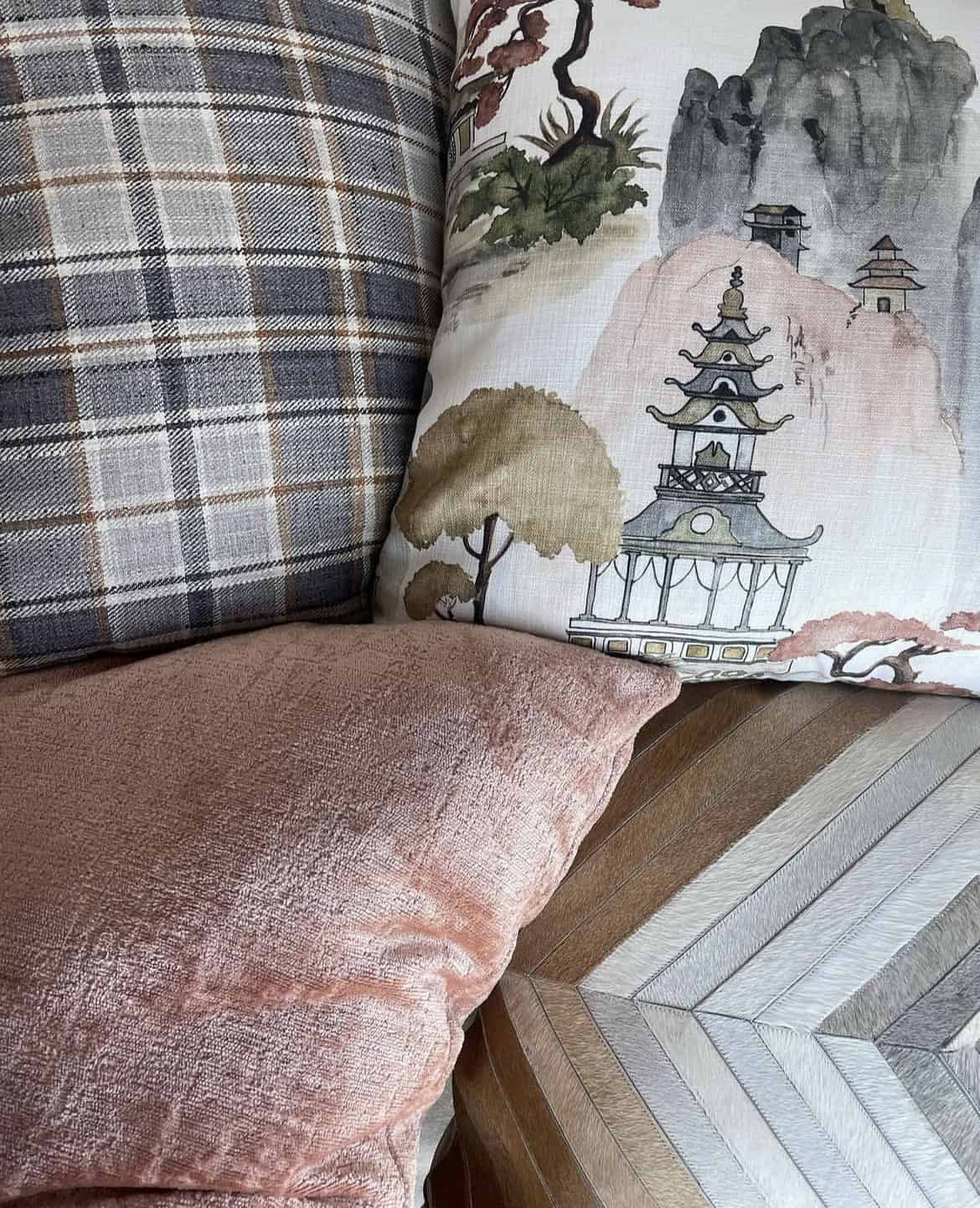 A photo of four decorative pillows in light fall colors, like blush pink and light brown.