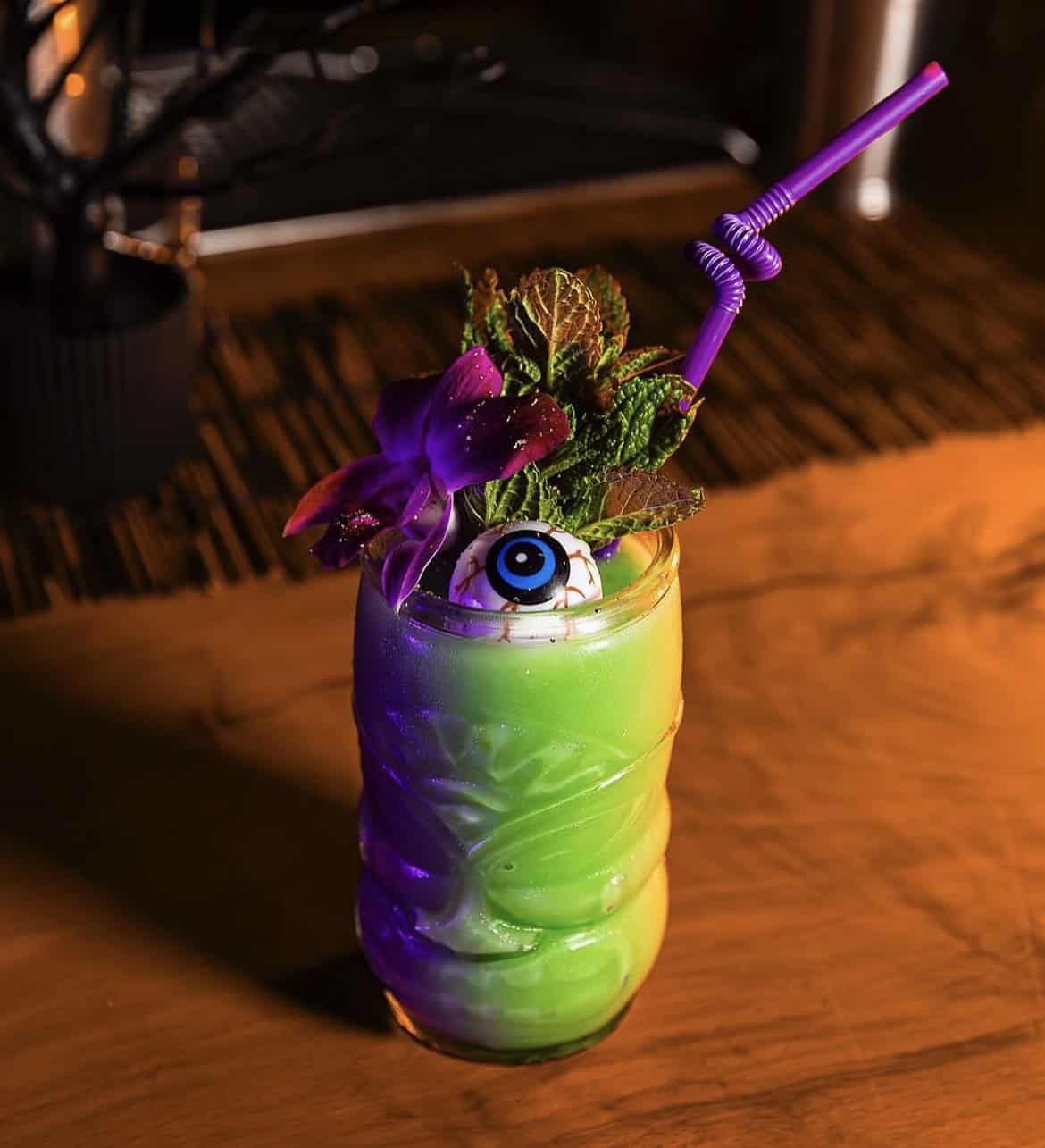 A photo of a bright green, tropical Halloween cocktail available at Butcher and the Rye.