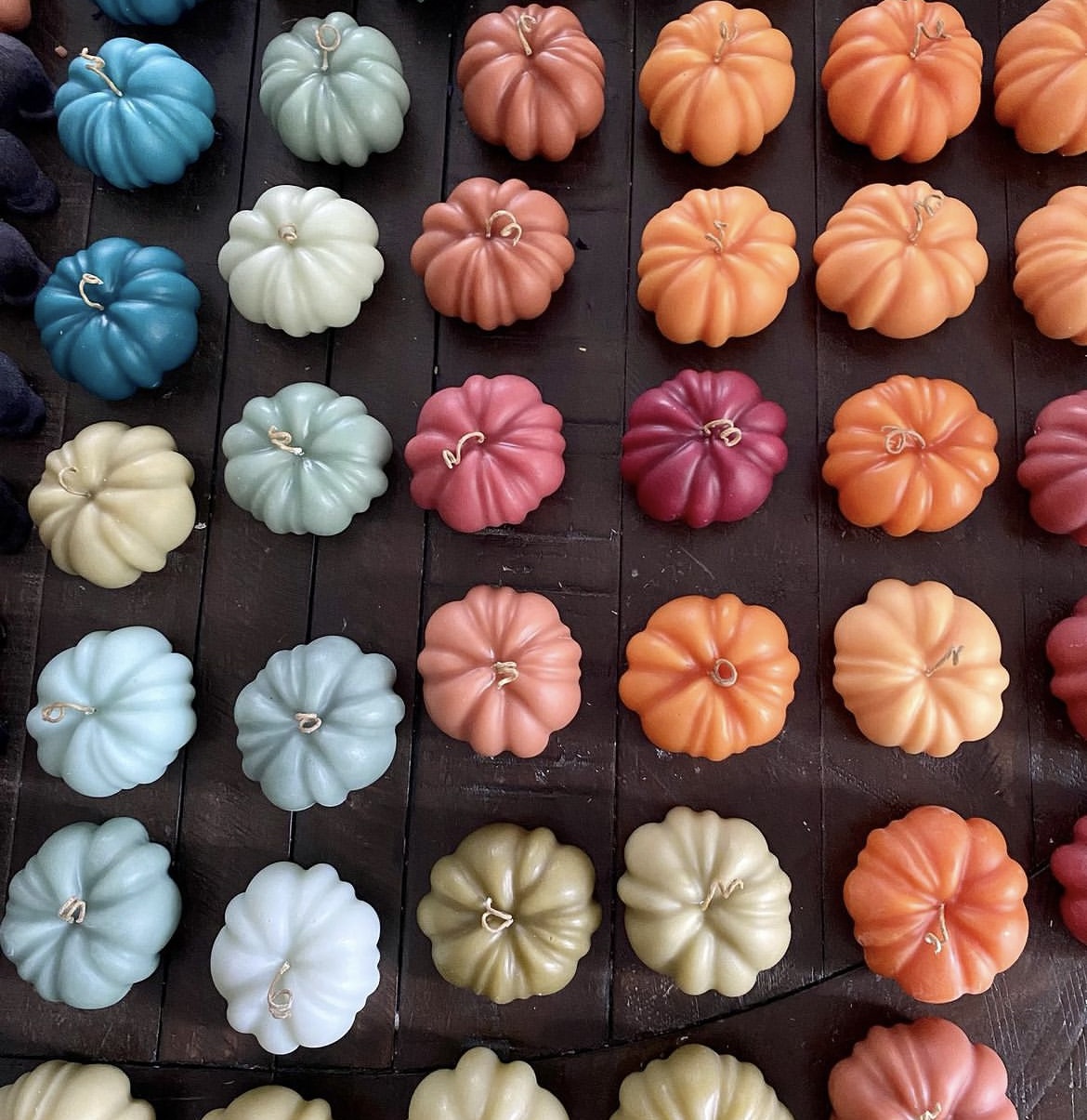 An overhead photo of different colors of mini pumpkin candles from Wicksburgh.
