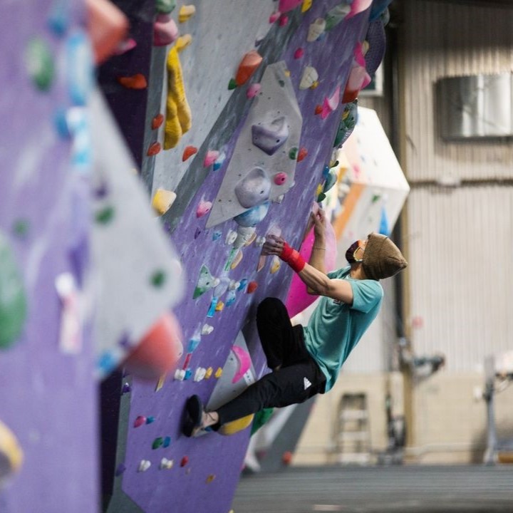 A person with a mask and gloves on, climbing at ASCEND.