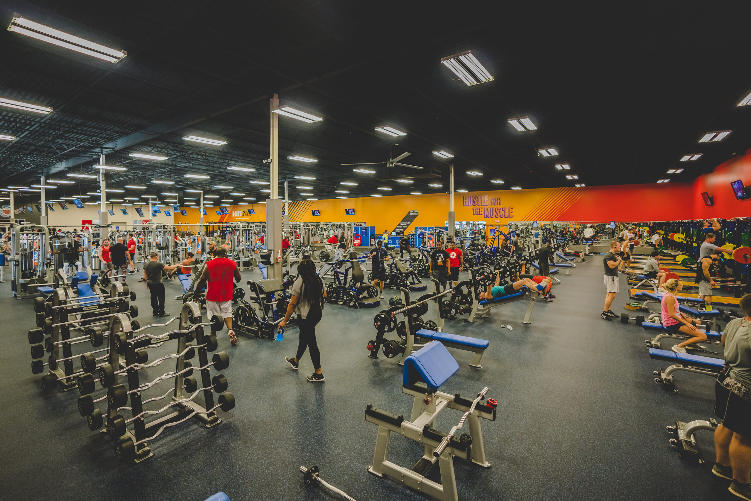 A large workout room at Crunch Fitness with free weights, machines, and bar weights.
