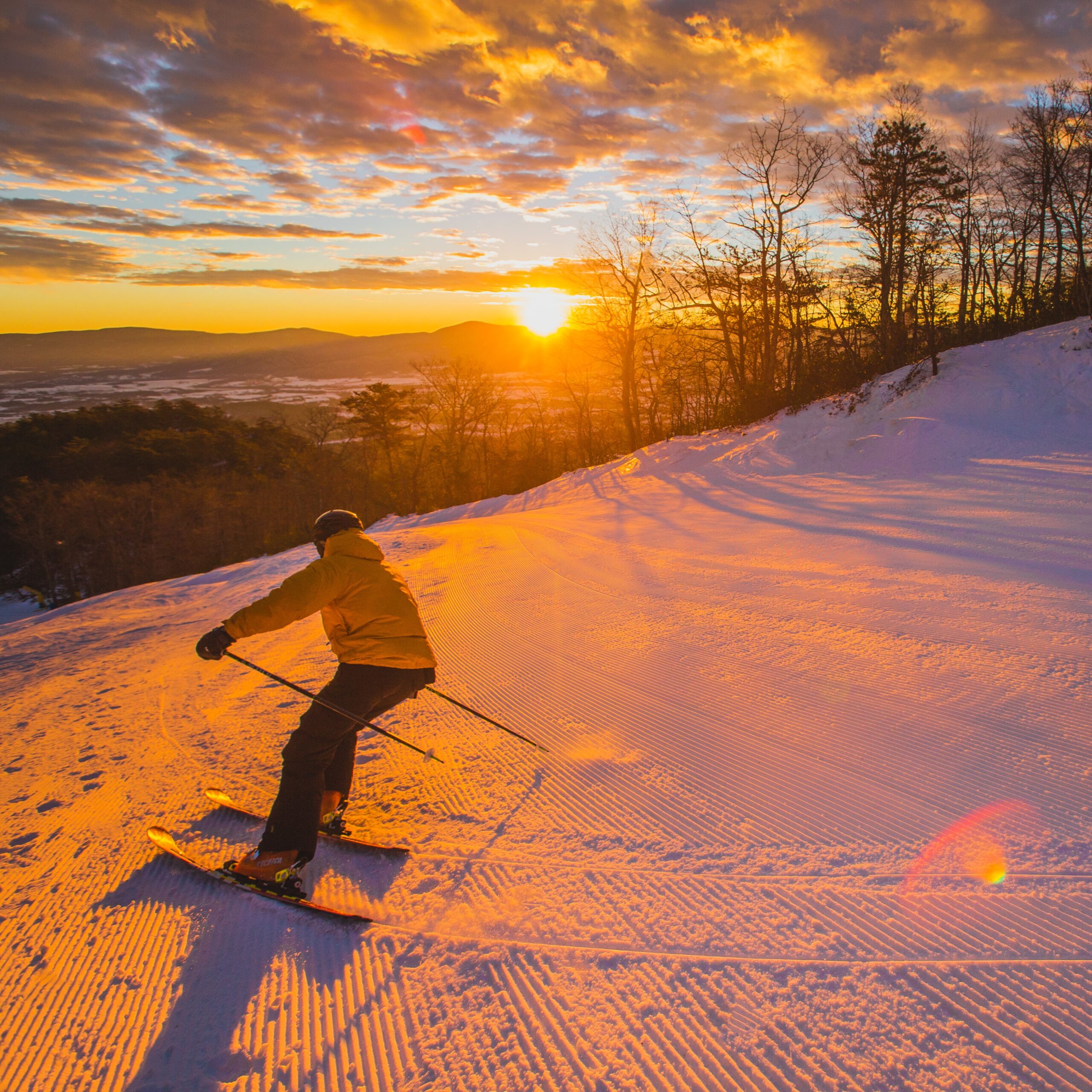 A photo of someone skiiing down a hill at sunset at Massanutten Resort.