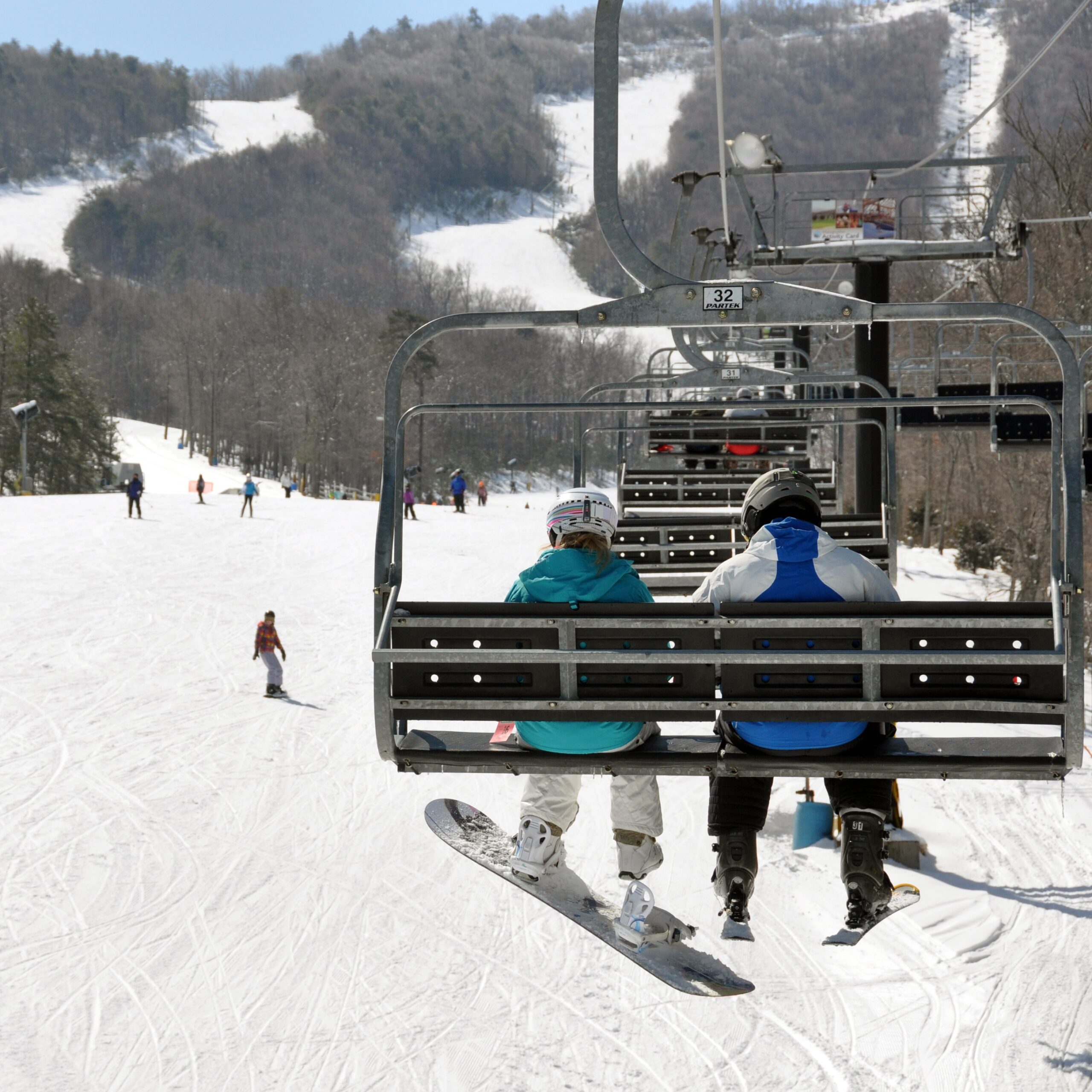 People on a ski lift above snowy mountains at Massanutten Resort.