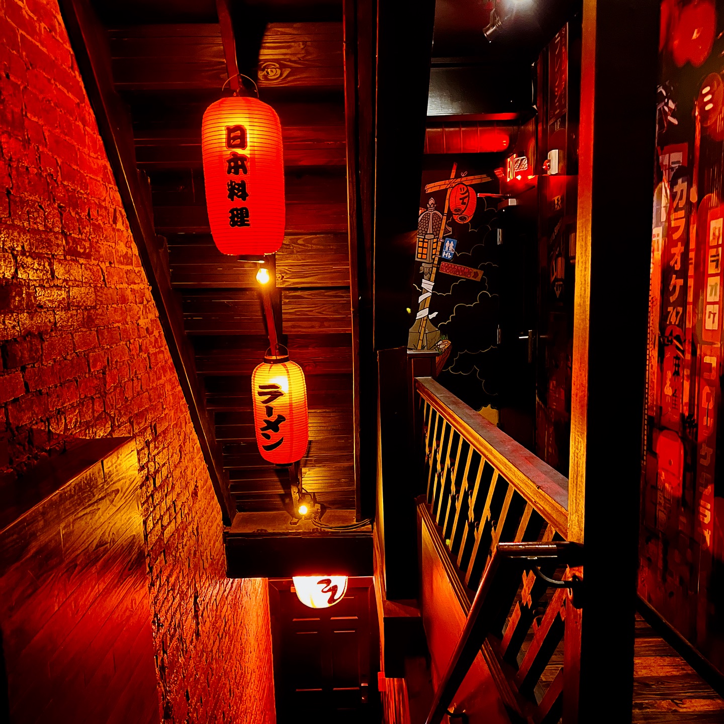 A photo of the inside of UmamiPGH. Red lighting is prominent, with traditional Japanese decorations.