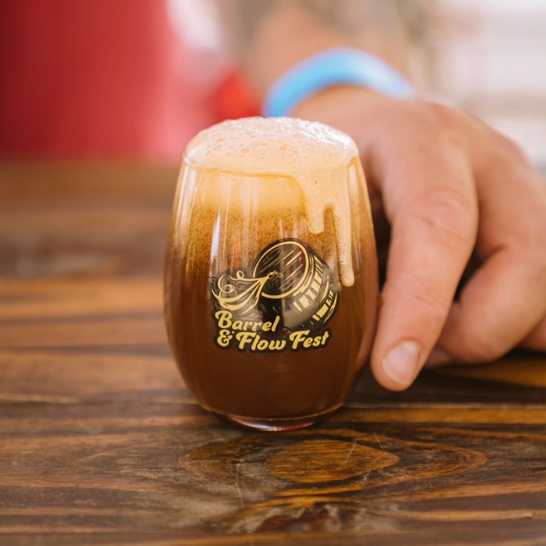 A small glass of beer with the Barrel & Flow Fest logo on it.