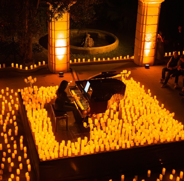 A woman playing piano surrounded by lit candles. Candlelight Concerts are a great place to visit for Galentine's Day in Pittsburgh.