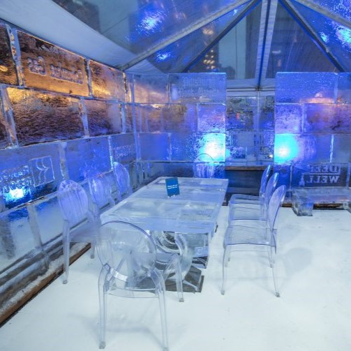 A photo of inside the ice house for Cool Down for Warmth. There is a table and chairs made of ice.