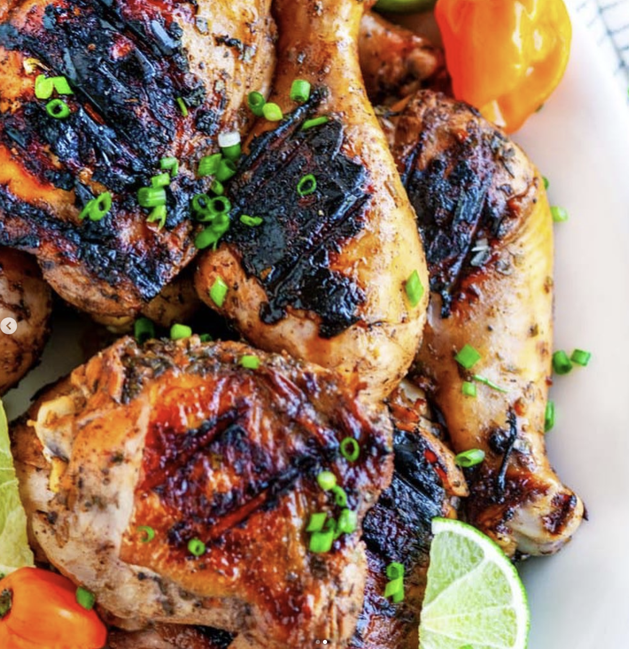 A photo of grilled chicken topped with green onions and lime.