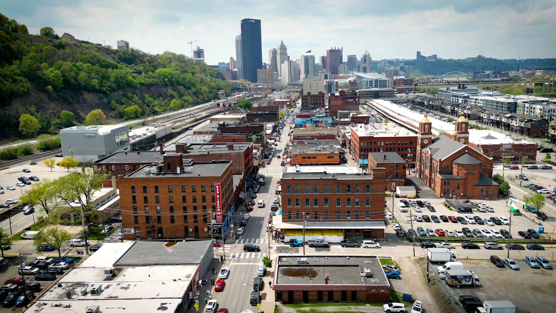 An overhead wide shot of the Strip District during the day with downtown in the background.