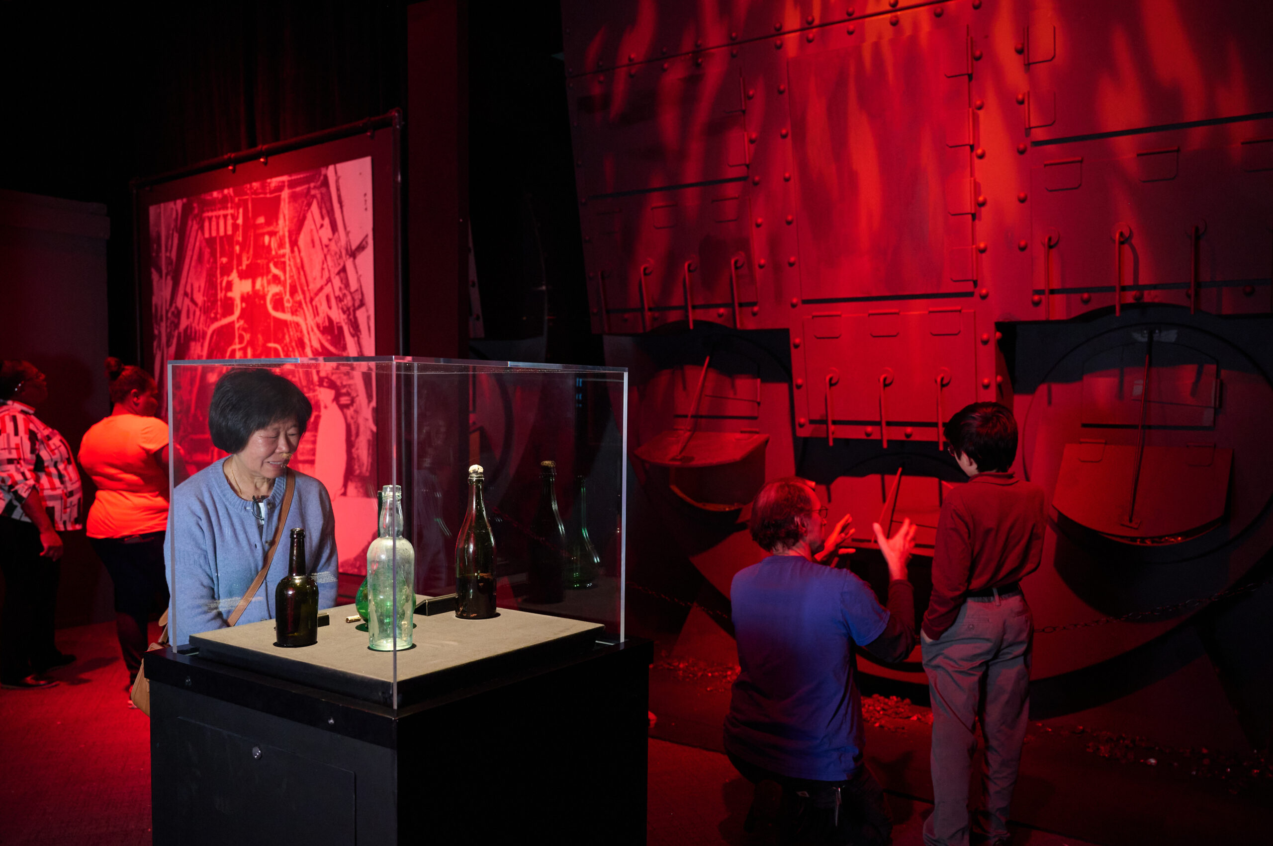 A photo of people looking at different parts of the exhibit, like glass bottles and images of the ship's interior.