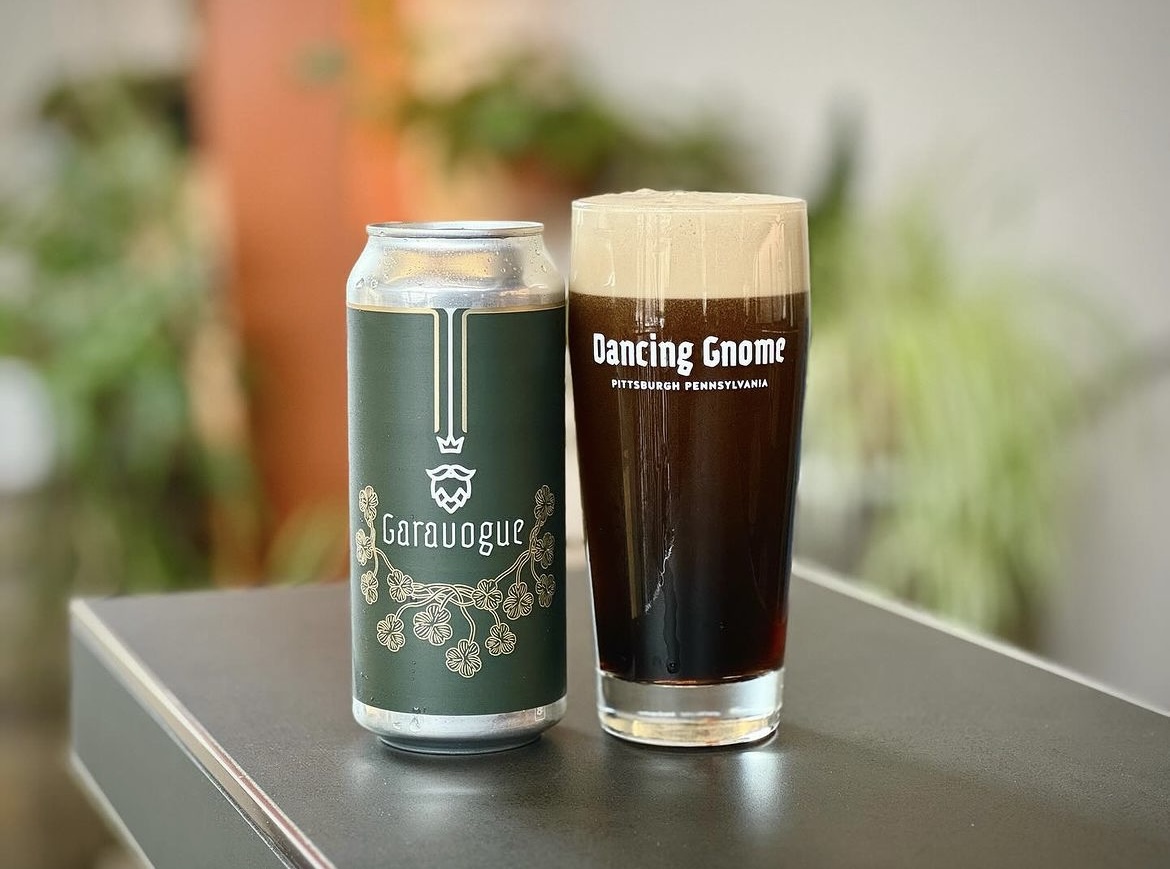 A photo of the Dancing Gnome's new brew, the Garavogue Dry Irish Stout. It is in a can and in a glass beside the can.