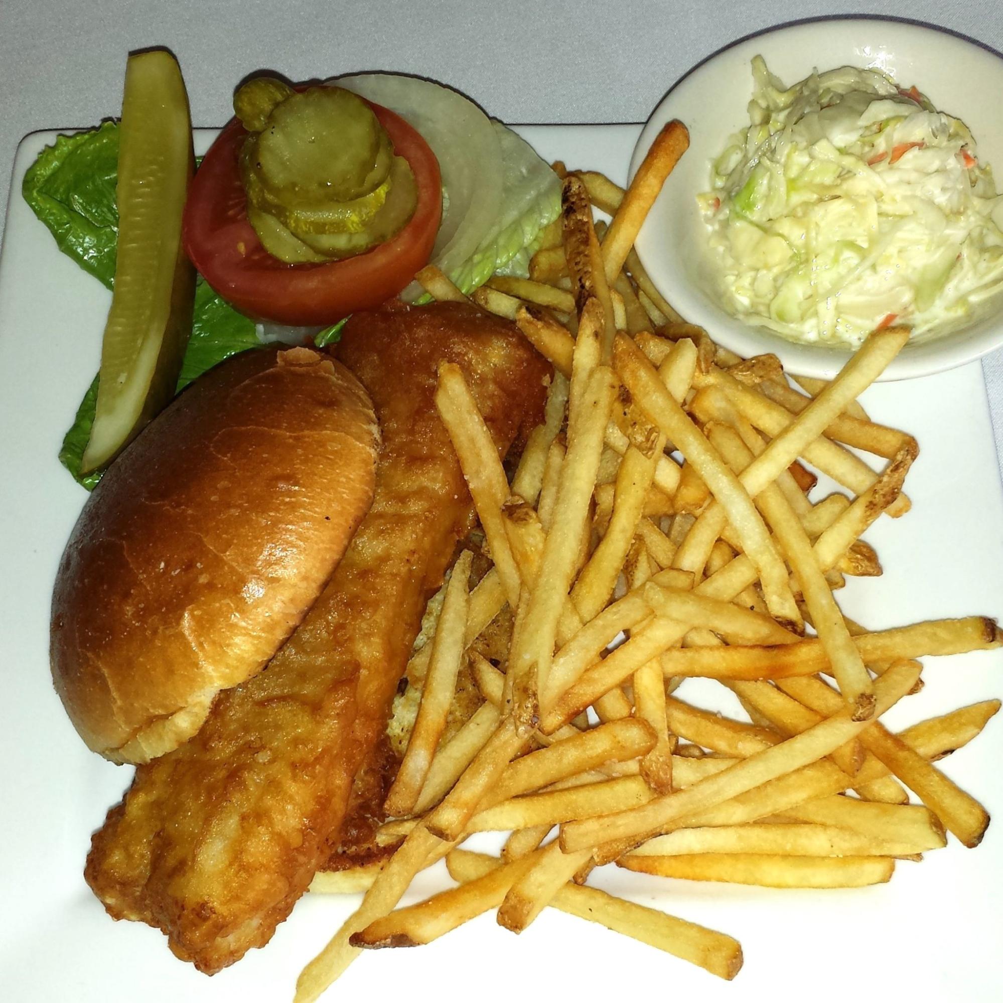 A plate of coleslaw, a fish sandwich, fries, and toppings from Hoffstot's Cafe Monaco.