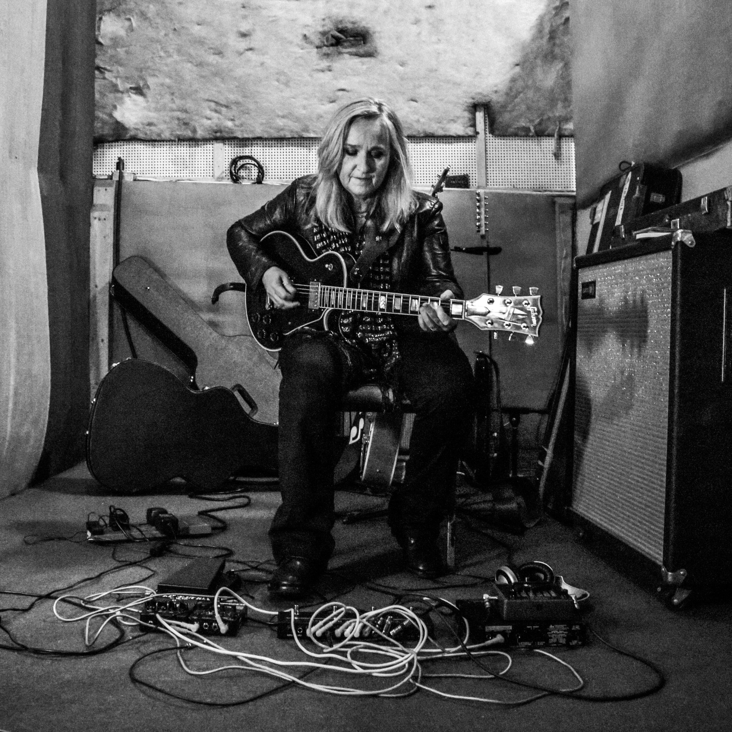 A black and white photo of Melissa Etheridge playing guitar.