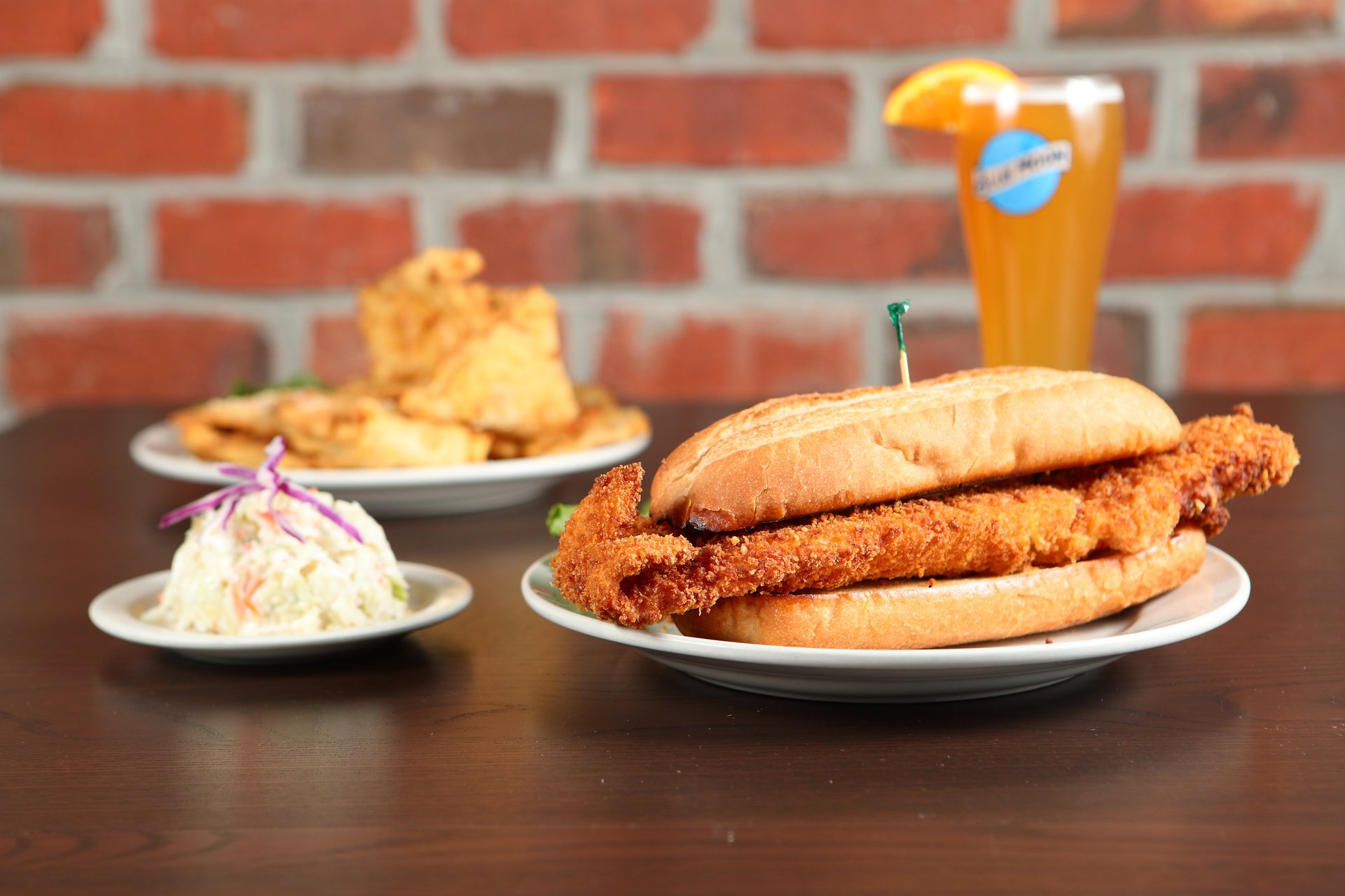 A photo from Sieb's Pub of a fish sandwich, side of coleslaw, another entrée item, and a Blue Moon in a glass.