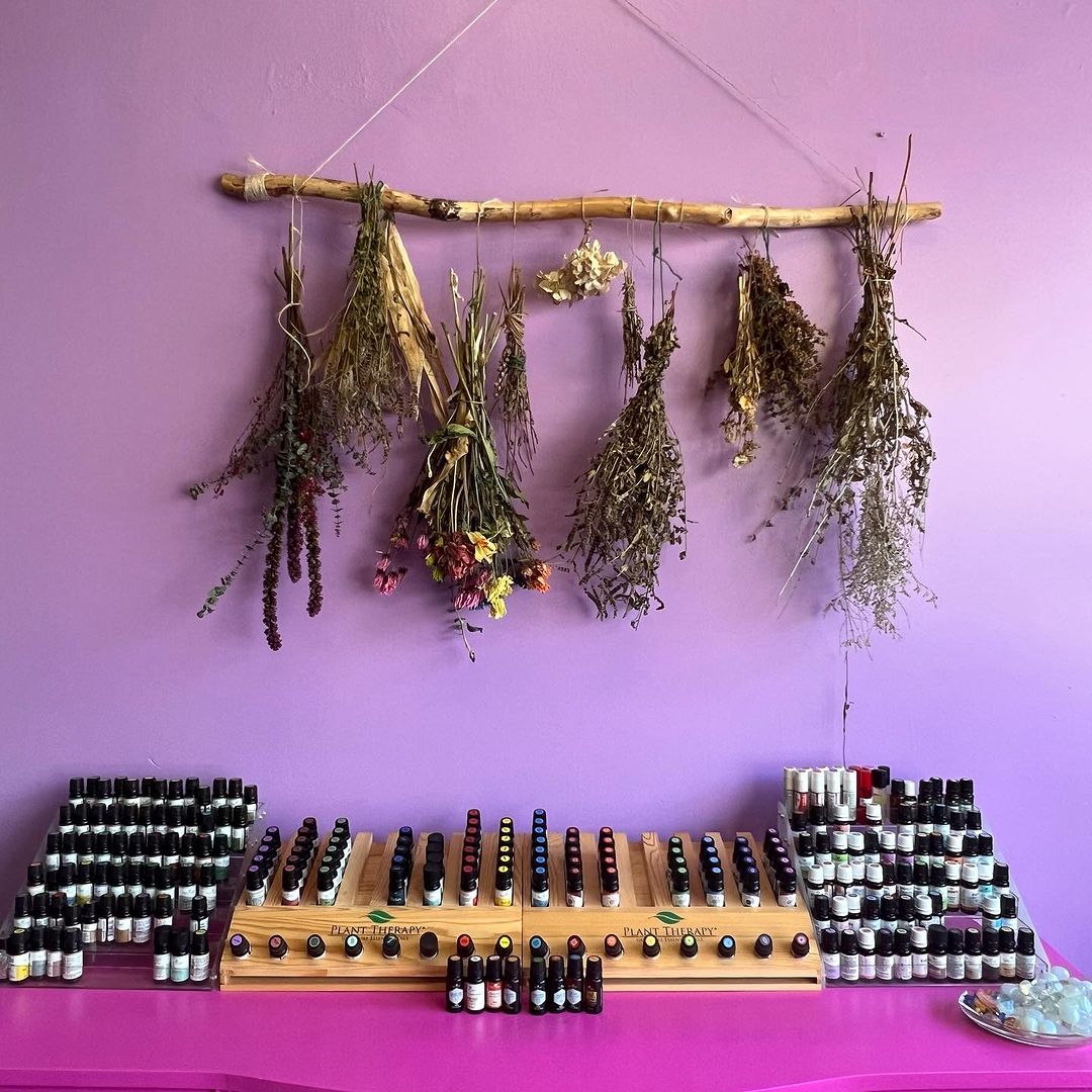 A photo of dried herbs hanging on the wall above an essential oil table at The Crow's Nest in Dormont.