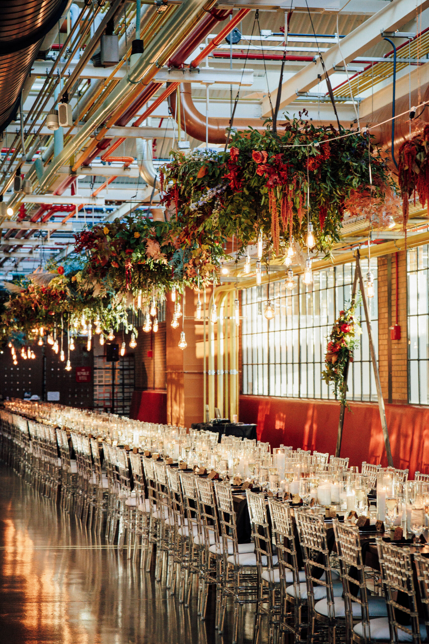 A photo of overhanging lights and foliage above a large wedding reception table.