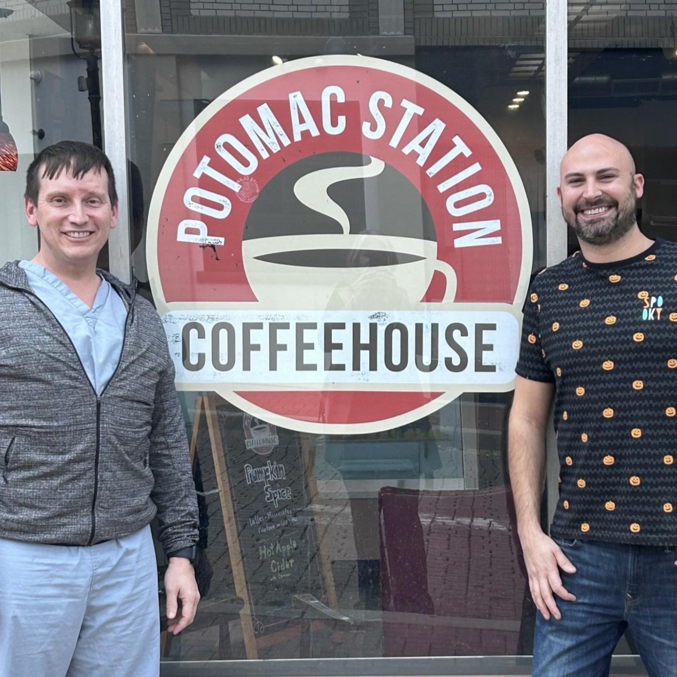 A photo of two men standing outside Potomac Station Coffeehouse's storefront logo.