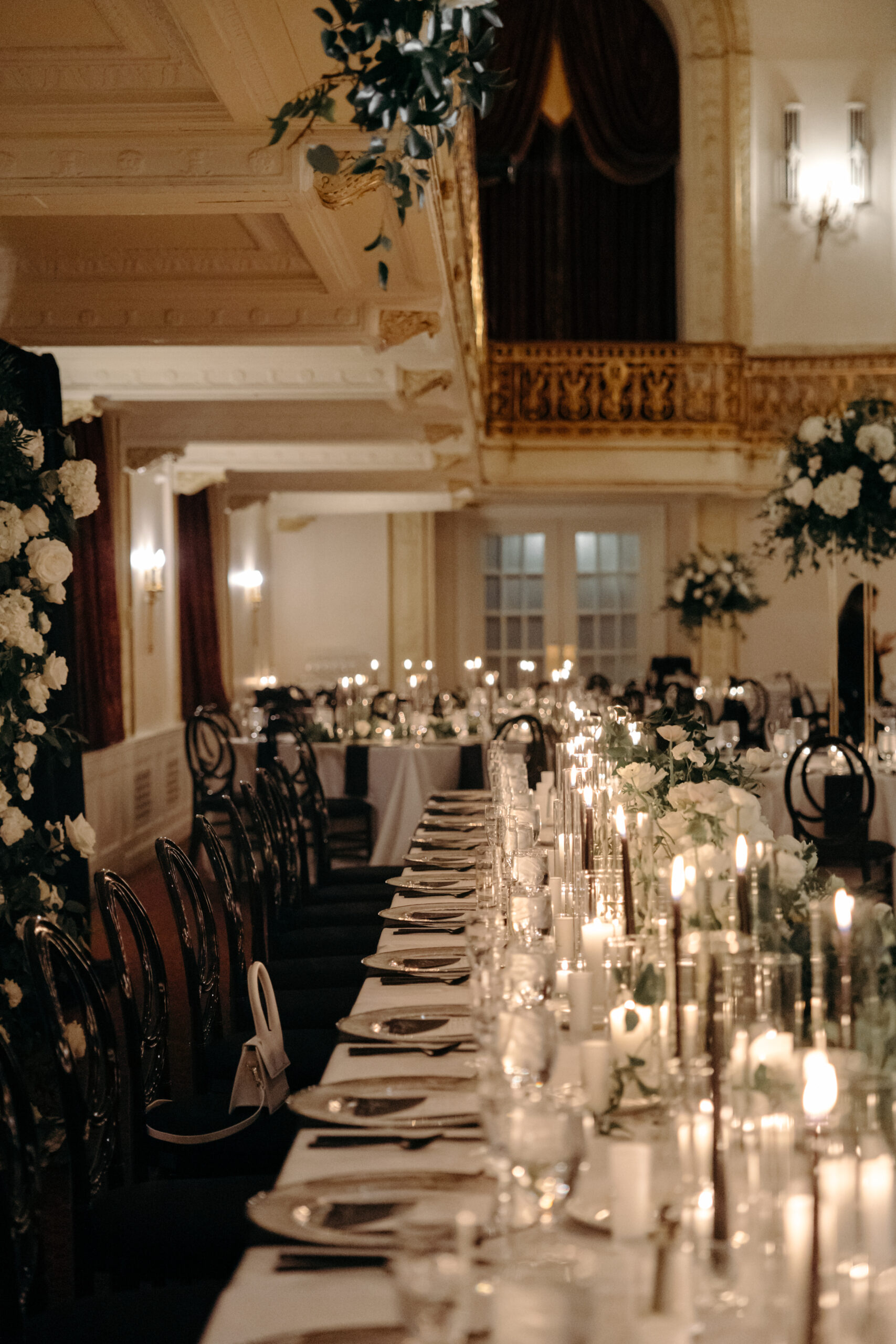 A photo of tables and chairs set for dinner at a wedding, with lit candles and centerpieces.