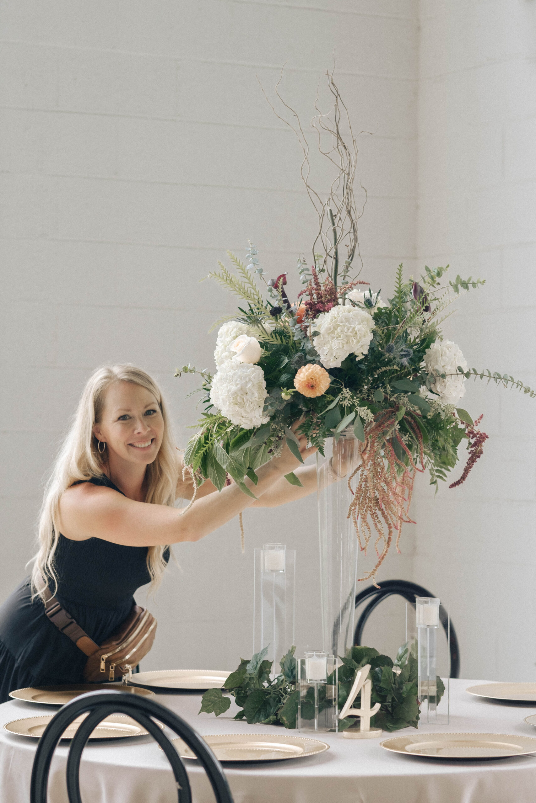A photo of a woman setting up a table centerpiece for a wedding.