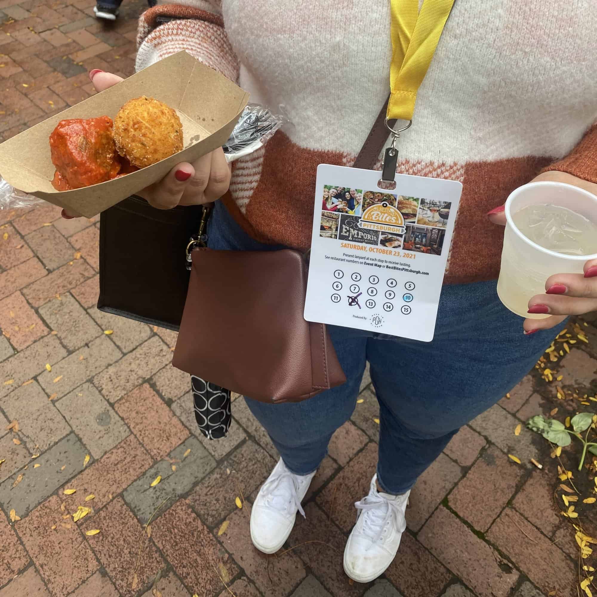 A person attending Best Bites holding a drink and a bite.