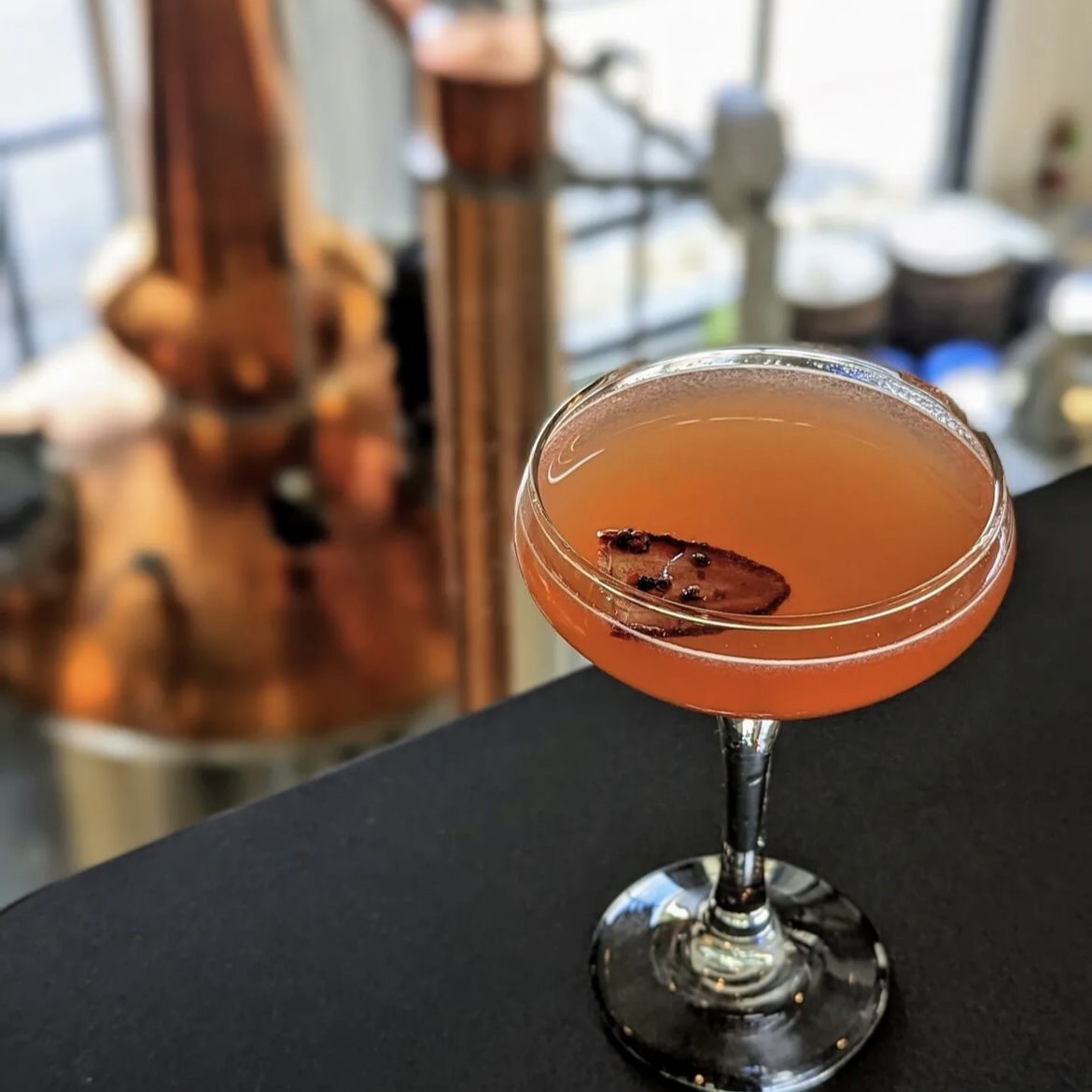 A photo of The Offensive Strawberry Daquiri cocktail on a ledge overlooking the manufacturing floor at Maggie's Farm Rum's distillery.