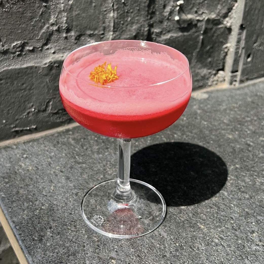 A photo of the Cosmic Yin cocktail with a hibiscus flower topping.