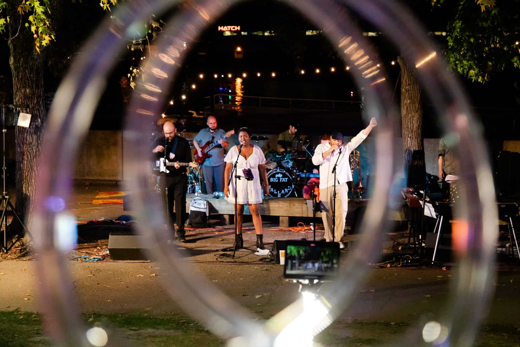 A photo of a band performing outside the Carnegie Science Center, near the river.
