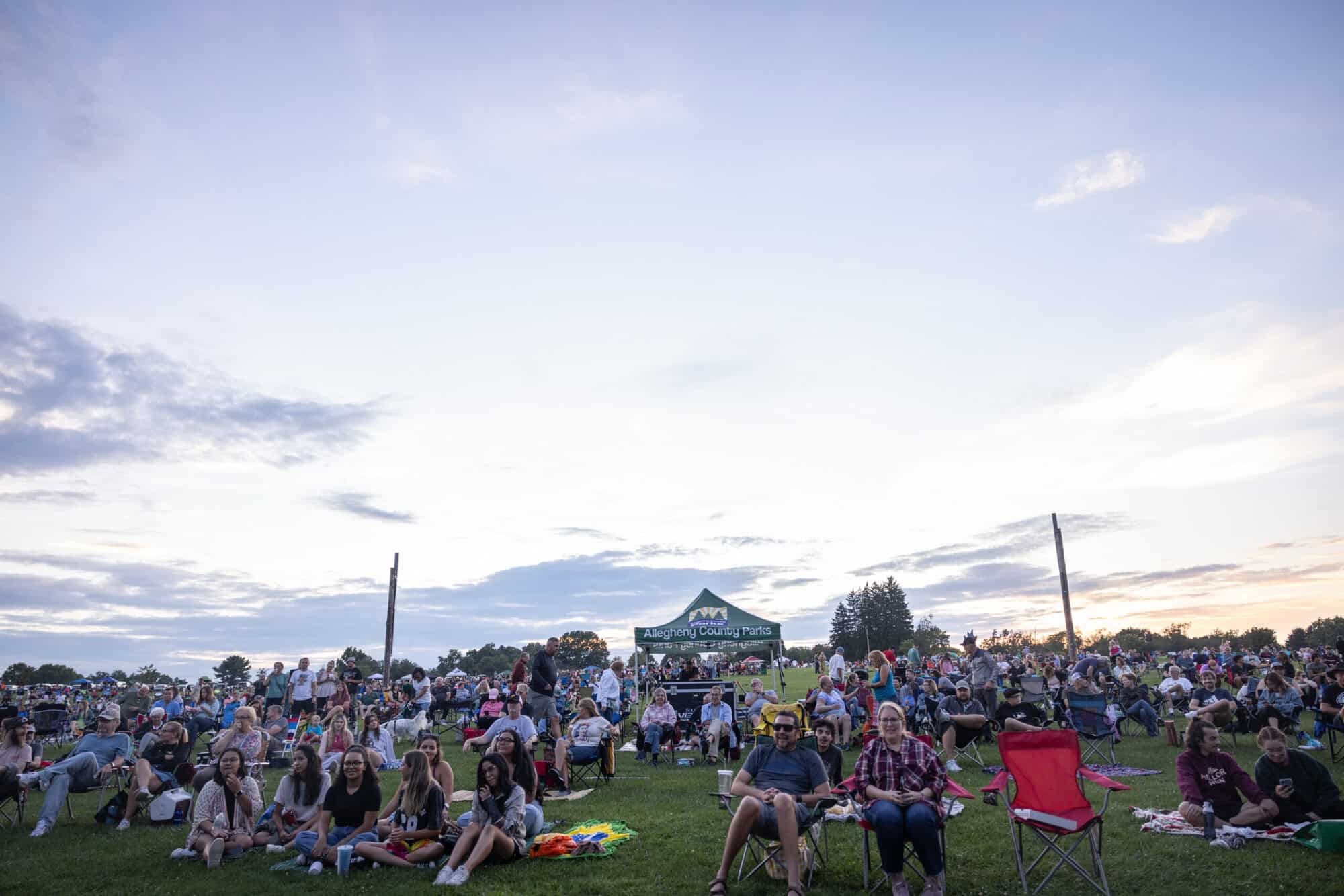 A photo of people sitting outside at an Allegheny County park for an outdoor concert.