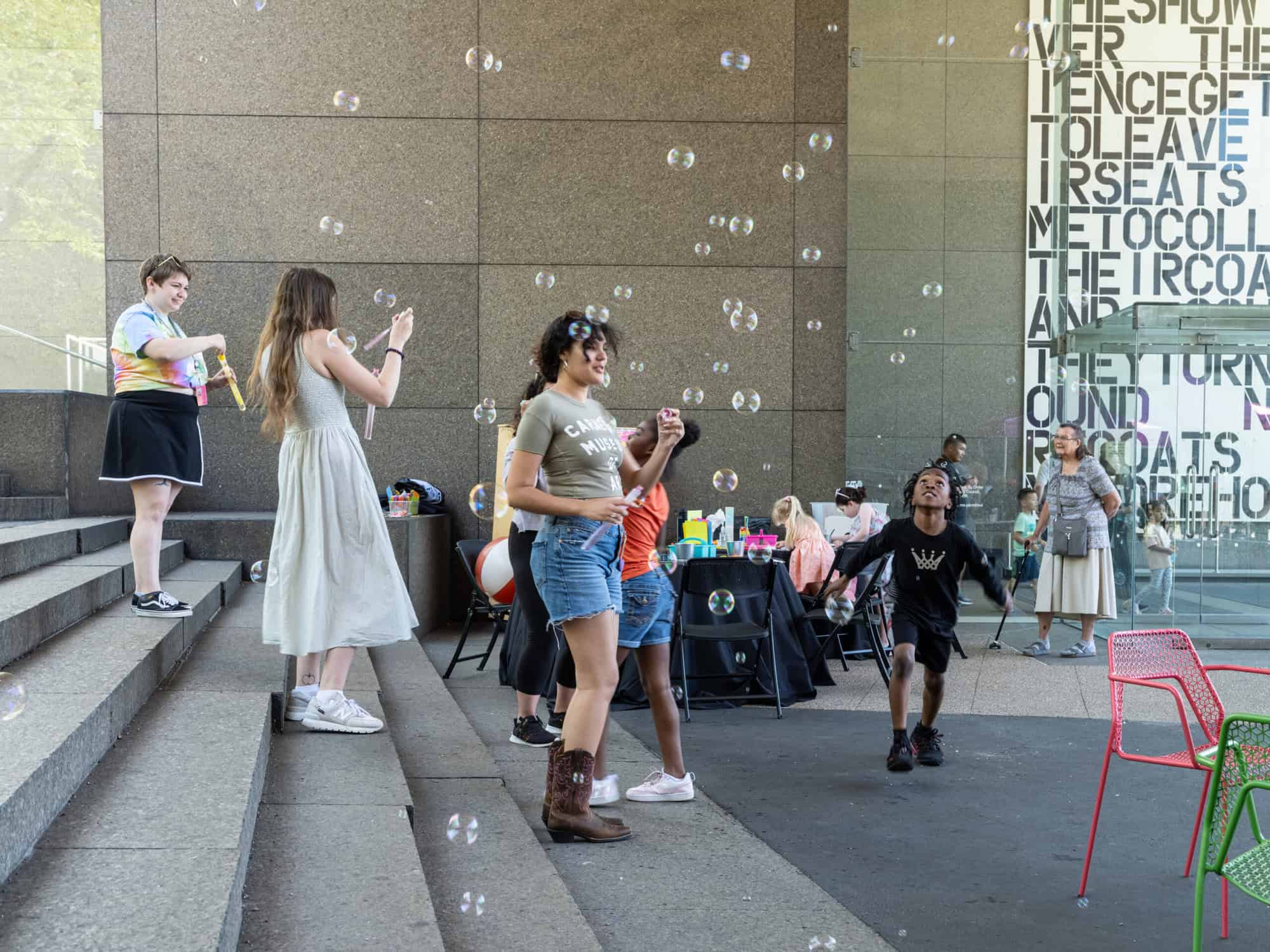 Adults and children playing with bubbles outside the Carnegie Museum of Art.