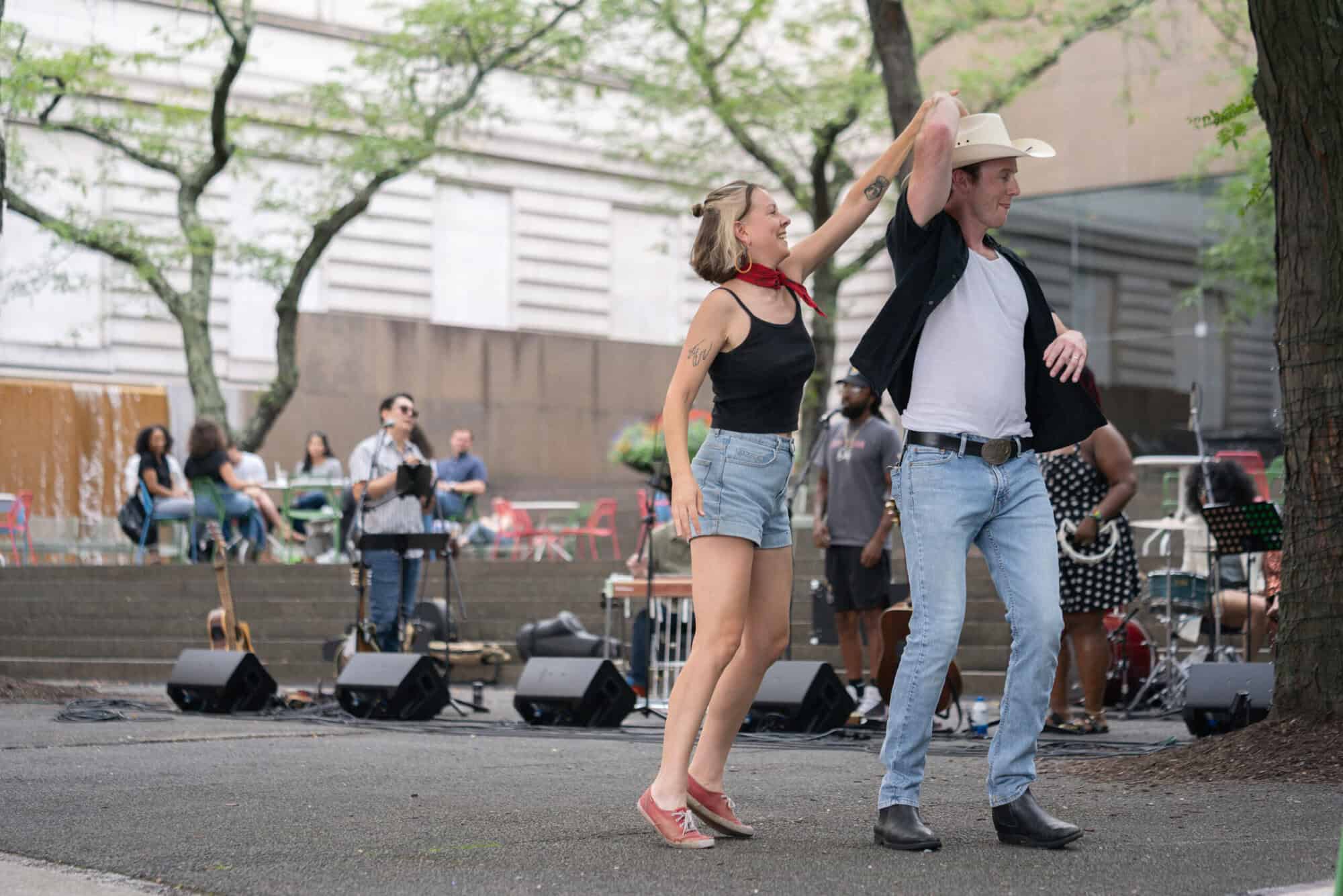 A photo of a man and woman dancing in front of a band by the steps outside Carnegie Museum of Art.