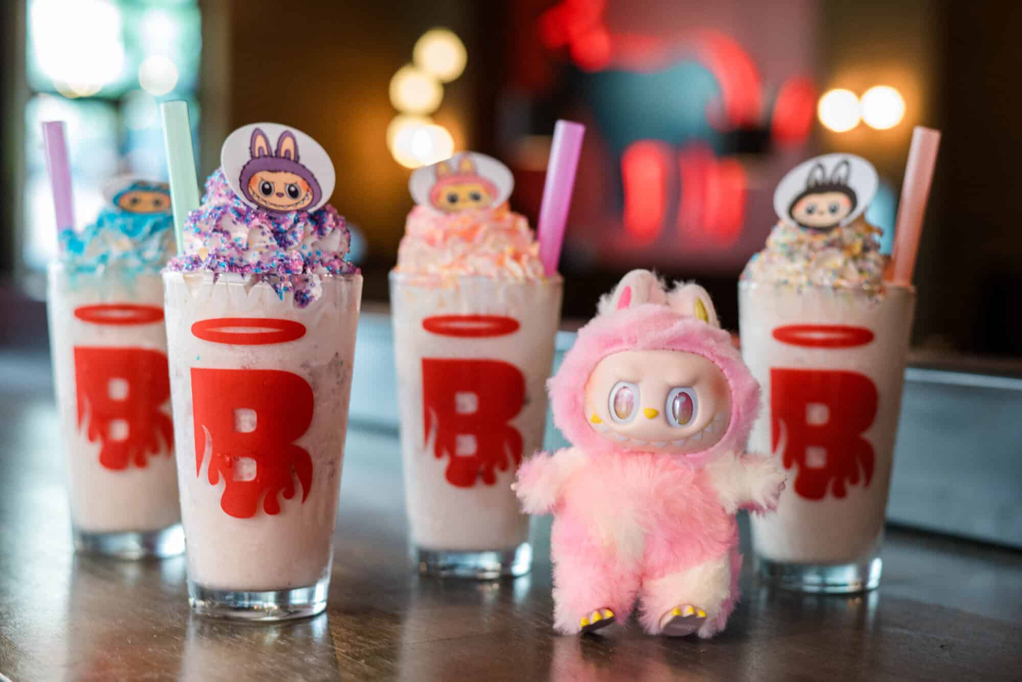 A photo of four Labubu Berry milkshakes next to a Labubu toy at Burgatory.
