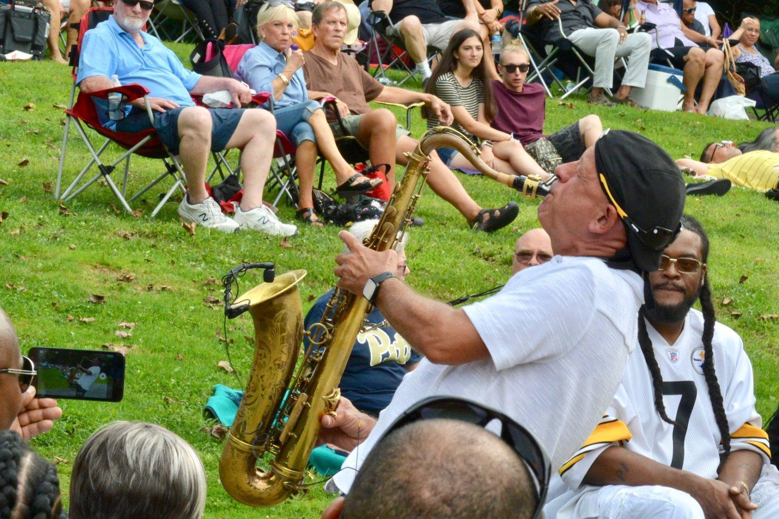 A photo of a man playing the saxophone in the crowd area at the Monroeville Jazz Festival.