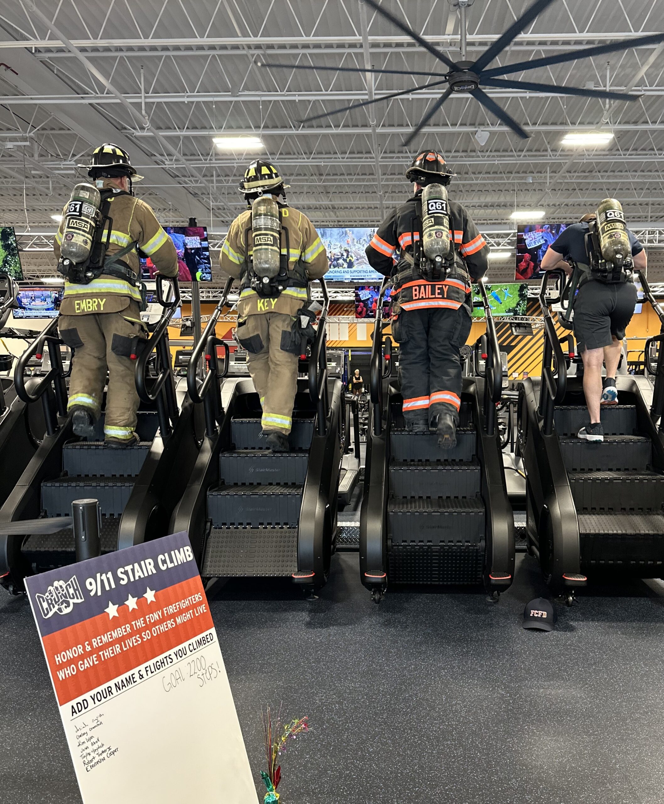 A photo of four firefighters in full gear doing the 9/11 Stair Climb Challenge at Crunch Fitness.