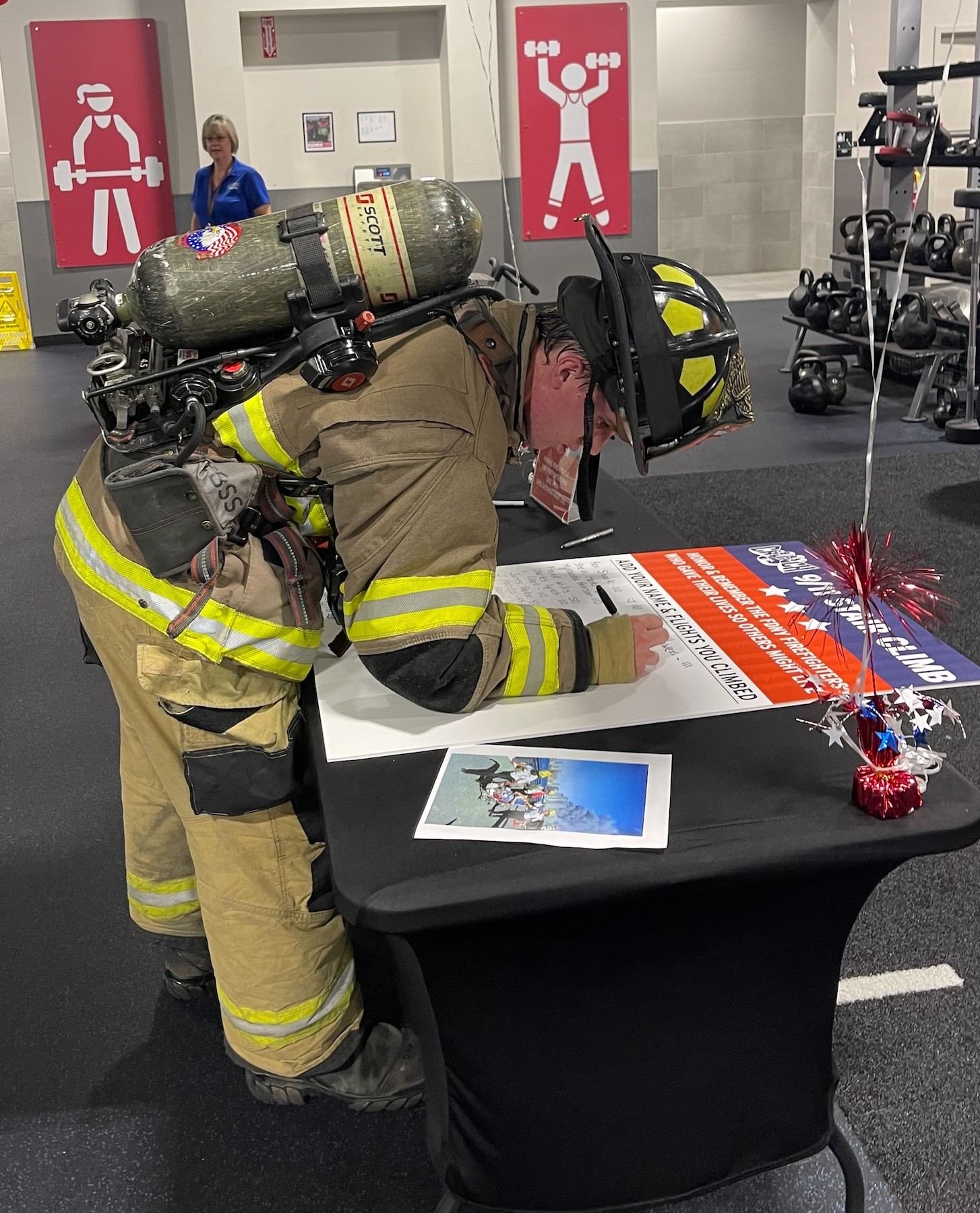 A photo of a firefighter in full turnout gear signing his name on the 9/11 Stair Climb board.