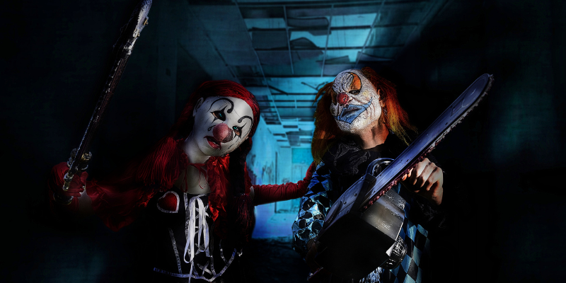 A photo of people in clown costumes holding chainsaws.